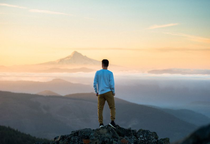 Hidden Travel - man standing on top of mountain