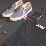 Mens Fashion - folded black Play shirt beside iPhone X, digital watch, and sneakers